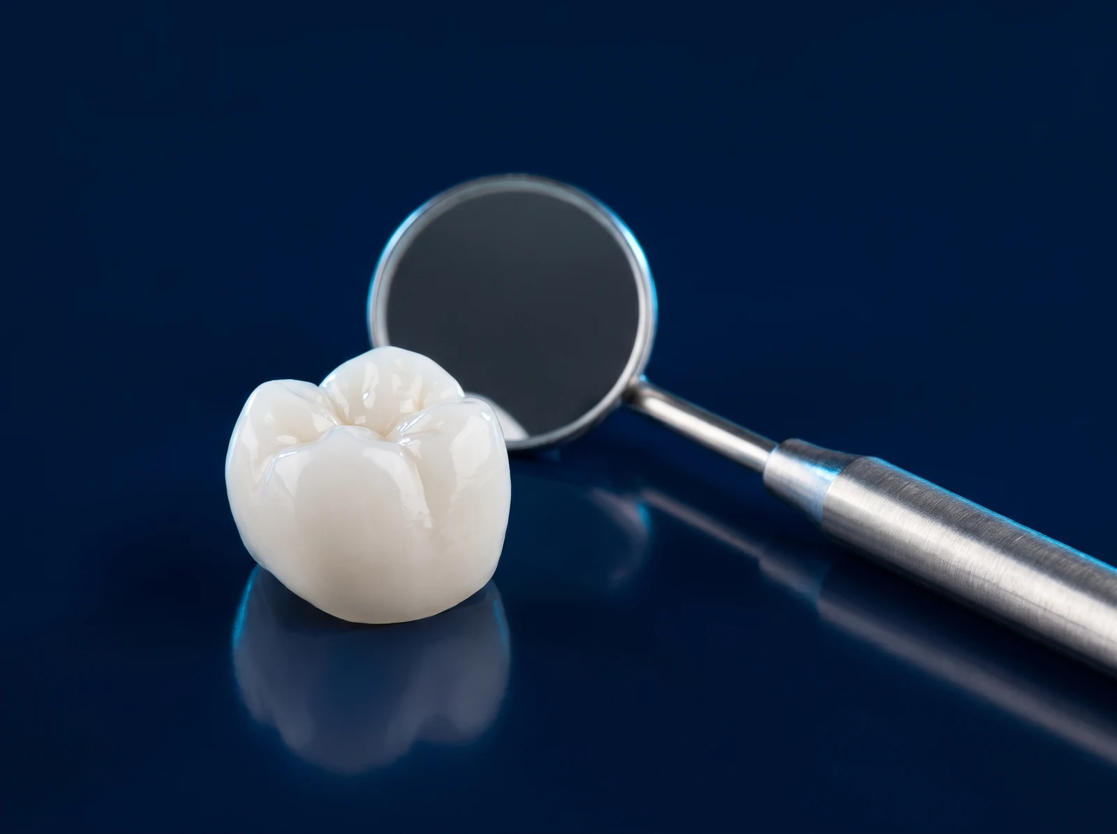 Clinical render of a ceramic crown and a dental mirror on a deep blue surface