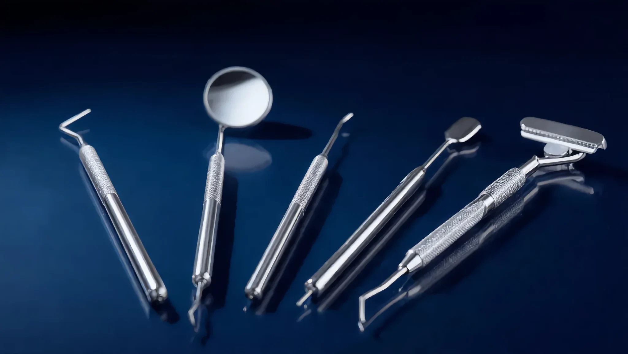 Clinical render of five dental hand instruments fanned on a dark blue surface