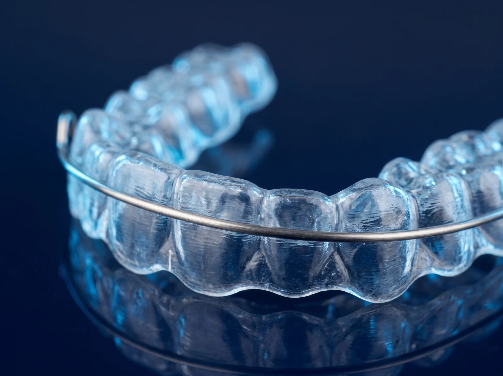 Clinical render of a clear orthodontic retainer with a thin wire on a deep blue surface